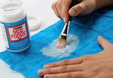 Spreading Fabric Mod Podge on a piece of fabric using a paint brush