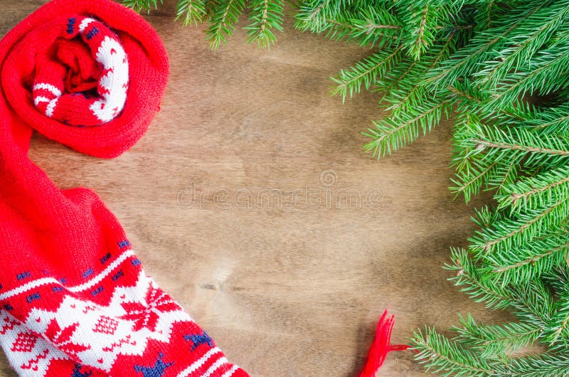 Knitted warm winter scarf and branch fir tree on rustic wooden background with copy space. Christmas background. Top view stock images